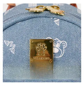 Detail of blue denim backpack with white bear prints and golden metallic bear zipper pulls