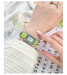Close-up of a vintage square watch with green leather strap and diamond-set silver case