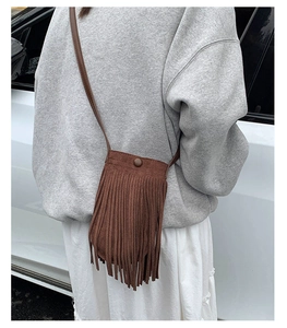 Gros plan d'un sac à bandoulière en daim marron à franges avec une tenue d'automne décontractée