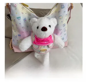 Close-up of a white plush bear charm featuring a pink bib and cute cartoon crossbody bag