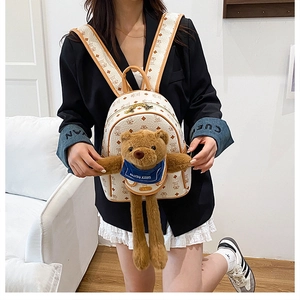 Dettaglio mini zaino crema con motivo monogramma e ciondolo orsetto di peluche