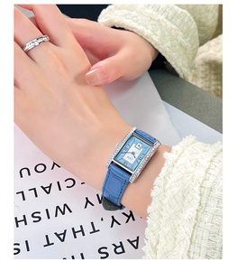 Wrist shot of a vintage square quartz watch with blue leather strap and diamond-set case