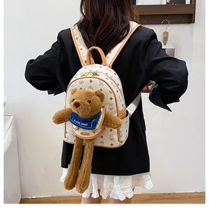 Dettaglio zaino bianco con motivo monogramma, orsetto di peluche 3D e zip dorata
