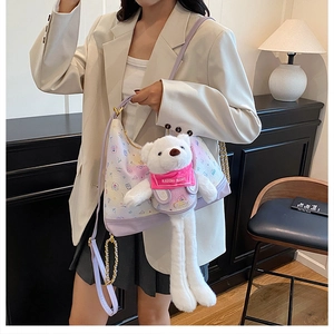 Detail of lavender plush shoulder bag with cartoon prints and a large teddy bear pendant