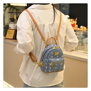 Detail of blue denim mini backpack featuring cute bear print and golden bear zipper charm