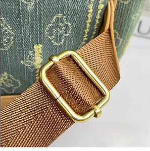 Detail of golden adjustable buckle on brown fabric strap of the floral denim backpack