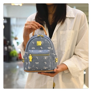 Detail of blue denim backpack featuring cute bear prints and gold bear-shaped zipper puller