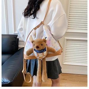 Detail of white printed crescent bag with plush bear charm and chain strap