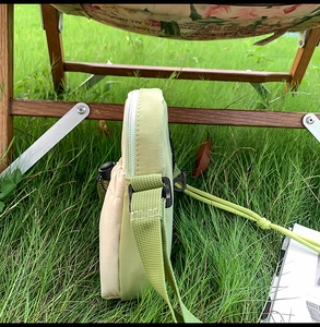 Detail view of a compact green and beige crossbody nylon bag with adjustable strap
