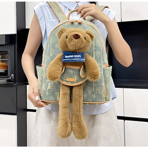 Detail of light green denim backpack with cute teddy bear plush and branded patterns