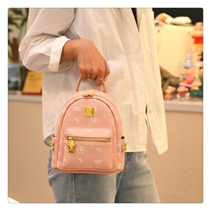 Close-up of pink mini backpack with bear pattern, heart-shaped zipper and gold hardware