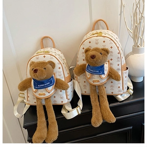 Dettaglio di due zaini orsetto di peluche color crema con motivo logo e sciarpe blu