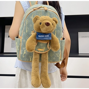 Detail of light green jacquard backpack featuring a cute plush bear and gold logo