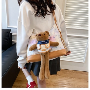 Detail of cartoon print shoulder bag with a large brown plush teddy bear charm