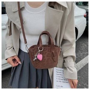 Detail of coffee brown faux suede handbag with leopard pattern and heart charm