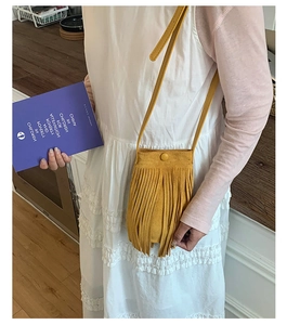 Détail du sac bandoulière en daim jaune gingembre avec franges denses et bouton pression