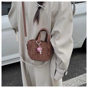 Detail of leopard print mini tote bag featuring a pink heart and silver key pendant