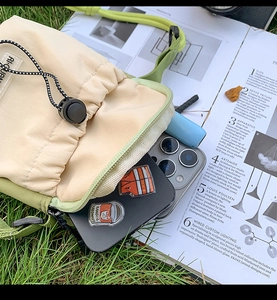 Close-up of canvas crossbody bag with drawstring closure on a magazine and grass
