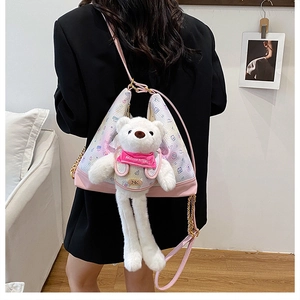 Detail of plush bear doll on pink crossbody bag with gold chain and cartoon prints