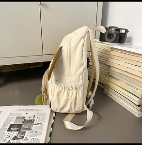 Detail view of the elastic side pocket and 3D decorative elements on the cream puppy backpack