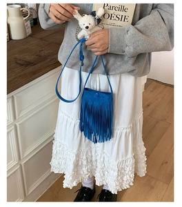 Vue détaillée d'un sac bandoulière bleu à franges avec un pendentif ours sur un mannequin