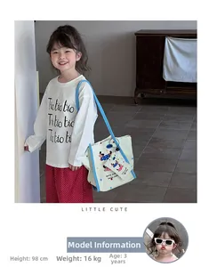 Détail d'un enfant portant un sac en toile chien vert et un pantalon à pois rouges