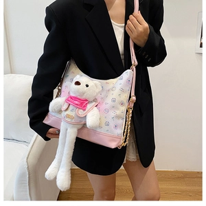 Detail of cute white leather handbag with printed cartoon patterns and plush bear charm