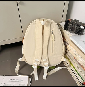 Detail of a beige dog-shaped backpack featuring a hidden zip pocket and padded straps