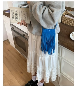 Détail d'un sac à bandoulière bleu avec franges denses et un bouton pression minimaliste