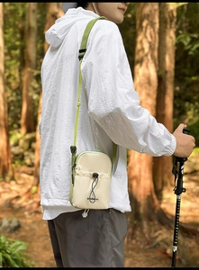 Detail of a lightweight nylon crossbody bag with drawstring pocket in nature setting