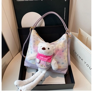 Detail of lavender crescent bag with cartoon prints and a white plush bear charm