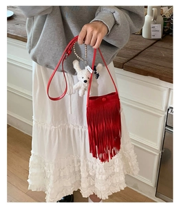 Gros plan d'un sac bandoulière rouge à franges avec un petit ours en peluche blanc