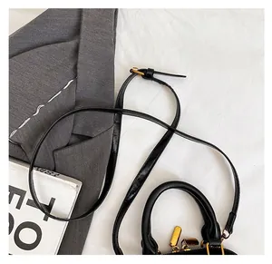 Détail du sac coquille en cuir noir avec fermeture dorée et bandoulière réglable
