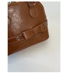 Detailed view of deep brown glossy leather bag with bow knot and silver metallic studs