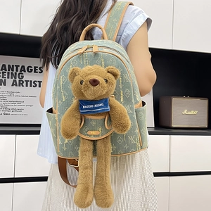 Cute green canvas backpack with teddy bear charm and brown leather trim for travel