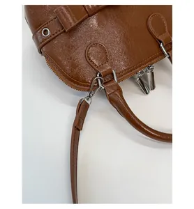Detail of detachable shoulder strap hook and metal zipper on brown vintage shell bag