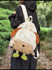 Detailed back view of a cute puppy-shaped backpack with a mini bear charm in a park