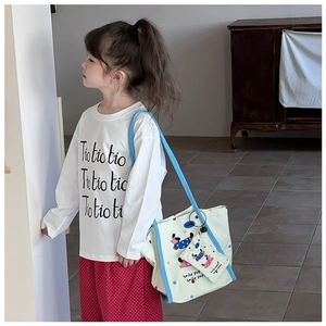 Détail du t-shirt blanc enfant avec pantalon à pois rouges et sac en toile à motif cartoon