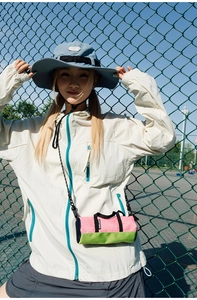 Detail of a mini cylinder crossbody bag with a sun hat and lightweight sports jacket