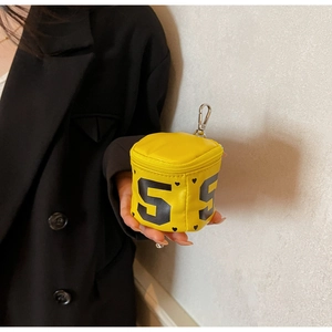 Close-up of yellow mini coin purse with number 5 print held by model in black blazer