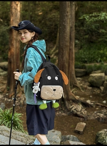 Outdoor shot of a black cartoon dog backpack featuring 3D ears and colorful details