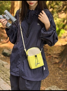 Outdoor lifestyle shot of a yellow nylon crossbody water bottle bag with drawstring pocket
