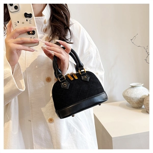 Detailed view of black quilted shell handbag with gold zippers and stylish metal feet
