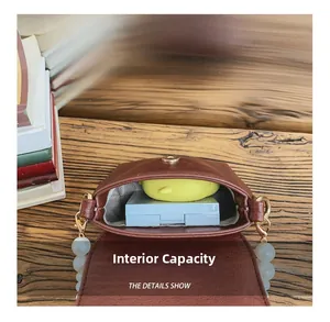 Interior capacity of brown leather mini bag with pearl strap on a wooden surface