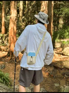 Detail of beige outdoor crossbody bag with drawstring closure in a natural forest setting