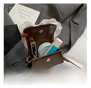 Detail view of brown leather mini bag interior with lace trim and magnetic closure