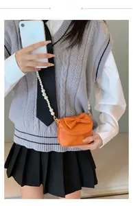 Detail of orange mini crossbody bag with bow decoration and elegant pearl chain