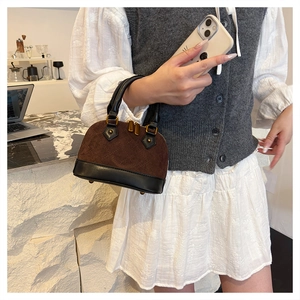 Close-up of mini quilted Boston bag in brown suede and black leather being hand-held