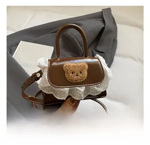 Close-up of plush bear patch and delicate white lace trim on the brown mini handbag