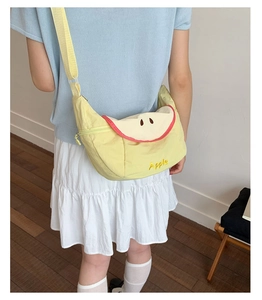 Detail of apple-shaped canvas crossbody bag with embroidery and adjustable strap